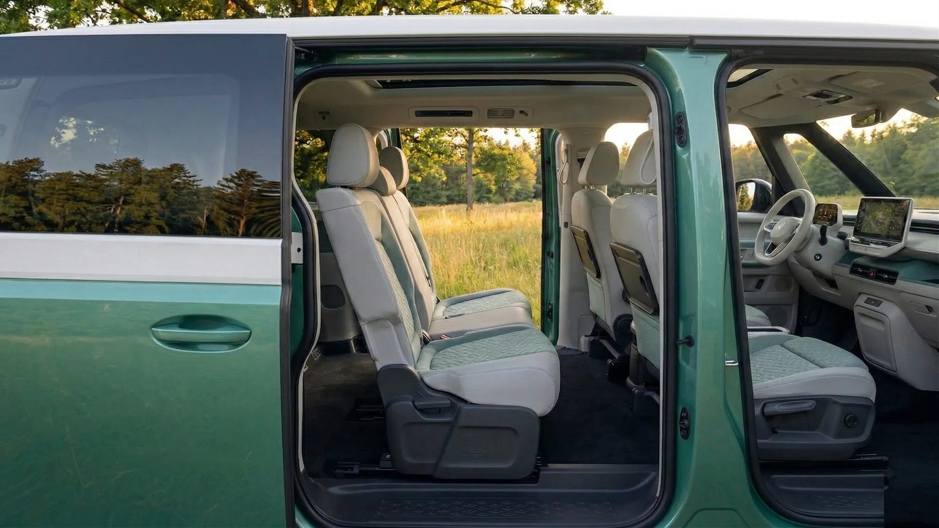 VW ID. Buzz interior showing spacious leather seats, dashboard, and infotainment screen through the open sliding door
